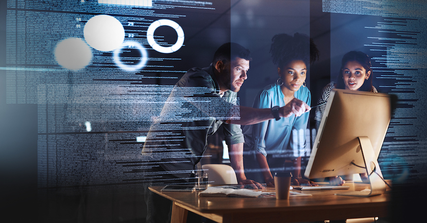 Shot of a group of programmers working together on a computer code at night